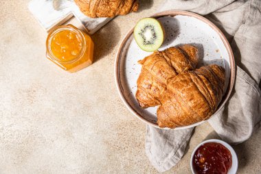 Reçelli Fransız kruvasanı ve hafif taşlı arka planda kivi. Lezzetli kruvasan. Üst görünüm.