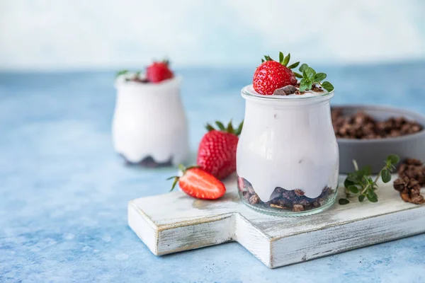 Здоровий сніданок або десерт з натуральним йогуртом, шоколадною гранолою та полуницею, синім бетонним фоном . — стокове фото