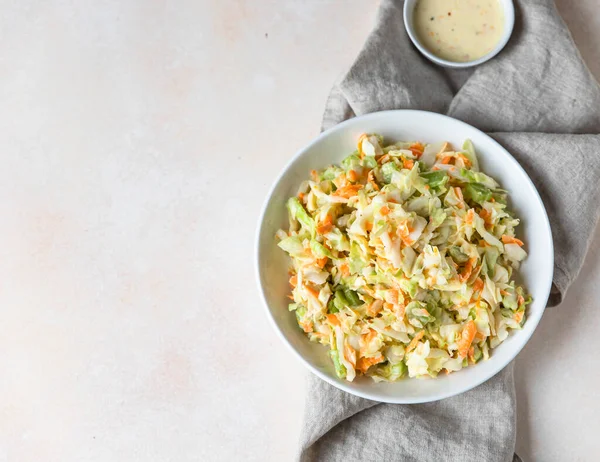 Coleslaw. Salad made of shredded white cabbage, grated carrot and rhubarb with orange mayonnaise dressing in white bowl. Top view. — Stock Photo, Image