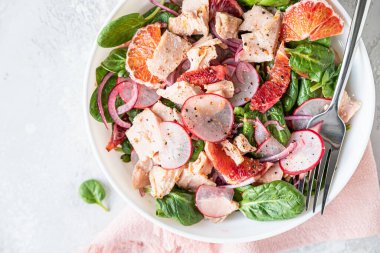 Somon salatası ıspanağı, turp ve kırmızı Sicilya portakalı, mavi beton arka plan. Keto ya da paleo yemeği. Üst Manzara. Seçici odak.