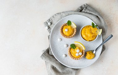 Limonlu mini tart, nane ve limon dilimleri, mini krema, açık beton arka plan. Üst Manzara. Uzayı kopyala Seçici odak.