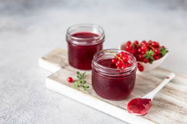 Ev yapımı frenk üzümü reçeli veya cam kavanozlarda reçel ve kırmızı frenk üzümü ahşap kesim tahtasındaki taze üzümler..