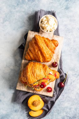 Nektarinli kruvasan, kiraz ve ricotta ya da ahşap kesim tahtasının üzerinde krem peynir. Seçici odaklanma. Üst görünüm.
