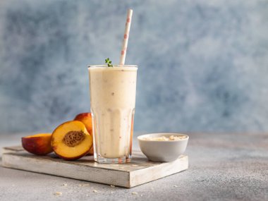 Mavi beton arka planda bir bardak nektarin smoothie. Yaz kokteyli ya da milkshake. Taze organik konsept. Seçici odak.