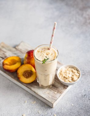 Mavi beton arka planda bir bardak nektarin smoothie. Yaz kokteyli ya da milkshake. Taze organik konsept. Seçici odak.