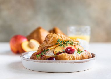 Krem peynirli kruvasan sandviç, nektarin ve kiraz ve lezzetli kahvaltı hazırlamak için taze malzeme. Seçici odak.