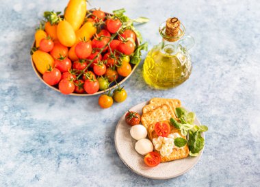 Kiraz domatesli krakerler, yeşil salata ve mozzarella, mavi beton arka plan. Seçici odak.