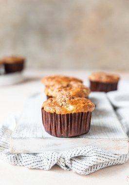 Beyaz kesme tahtasının üzerinde yulaf kırıntıları olan lezzetli kahvaltı çörekleri, açık beton arka plan. Seçici odak.