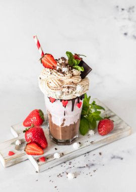 Çikolata ve çilekli milkshake ile birlikte dondurma ve krema, mini krema, çikolata, çilek ve naneli bardakta servis edilir. Seçici odak.