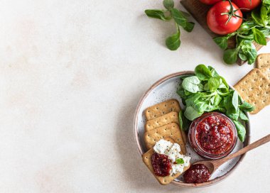 Domates reçeli, ziyafet ya da cam kavanozda kraker ve yeşil yapraklı salata sosu. Alışılmadık bir reçel. Akdeniz mutfağı. Seçici odaklanma. Üst görünüm.