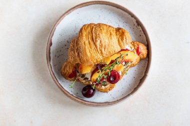 Krem peynirli, nektarinli ve kirazlı kruvasan sandviçi. en üstteki görünüm.