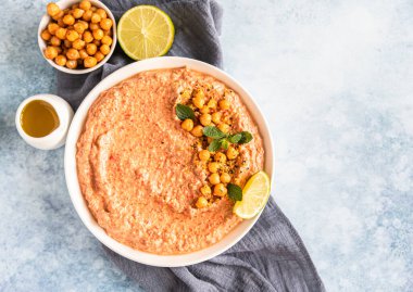 Nane ve limonla kavrulmuş kırmızı biberli humus garnitürü. Kırmızı dolma biber, limon ve naneli nohut püresi. Vejetaryen atıştırması. Üst görünüm.