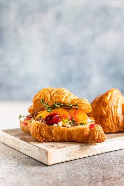 Croissant med nektarin, körsbär och ricotta eller färskost på skärbräda av trä. — Stockfoto