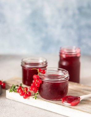 Ev yapımı frenk üzümü reçeli veya cam kavanozlarda reçel ve kırmızı üzümler ahşap kesim tahtasında taze üzümler. Seçici odak.