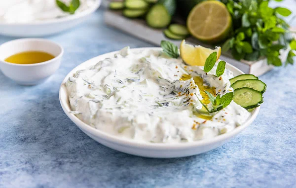 Hint veya Pakistan raita sosu veya salatalık, yoğurt, sarımsak ve nane, mavi beton arka plan. Geleneksel Hint mutfağı. Seçici odak.
