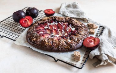 Ev yapımı galet ya da açık turta çikolatalı, erikli ve bademli açık beton arka planda.