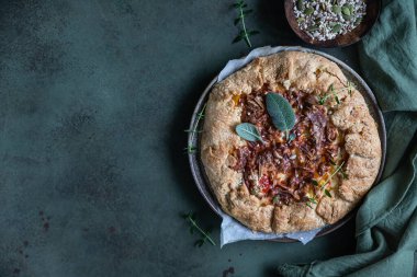 Baharatlı domates turtası, açık turta ya da domatesli galet ve yeşil çimento arka planda aromalı otlarla süslenmiş peynir..