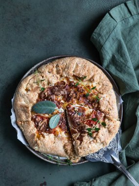 Baharatlı domates turtası, açık turta ya da domatesli galet ve yeşil çimento arka planda aromalı otlarla süslenmiş peynir..