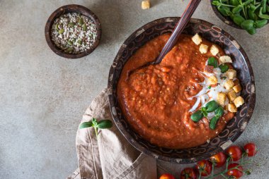 Kremalı ev yapımı domates çorbası, kızarmış ekmek ve çimento arka planda ahşap kasede mikroyeşil. Üst görünüm.