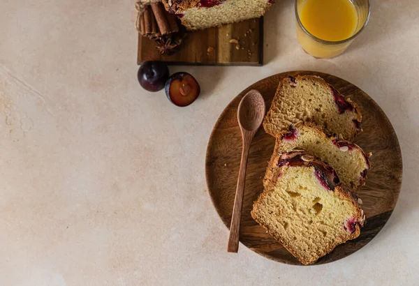 Homemade spicy plum cake decorated with almond on a wooden serving board, concrete background. Loaf cake with plum, spices and almond. — Stock Photo, Image