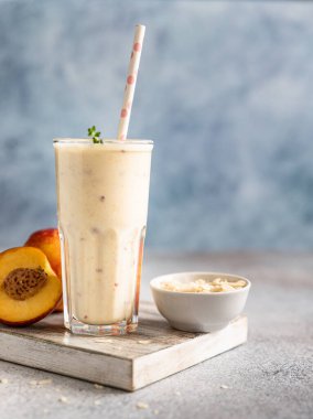 Mavi beton arka planda bir bardak nektarin smoothie. Yaz kokteyli ya da milkshake. Taze organik konsept. Seçici odak.