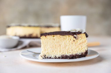 Çikolata jöleli ve bademli fırınlanmamış kremalı cheesecake dilimi, açık beton arka plan. Seçici odak.