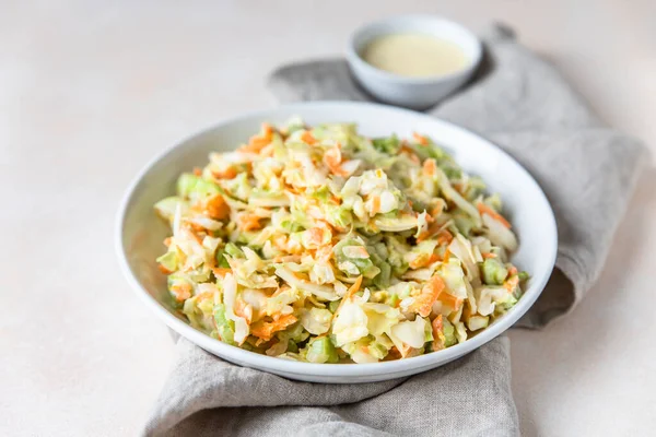 Капустный салат. Салат из измельченной белой капусты, тертой моркови и ревеня с апельсиновым майонезом в белой миске, светлый фон. — стоковое фото