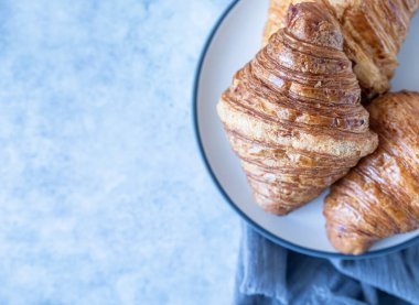 Lezzetli çıtır kruvasanlar, mavi beton arka plan. Seçici odaklanma. Üst Manzara. Boşluğu kopyala.