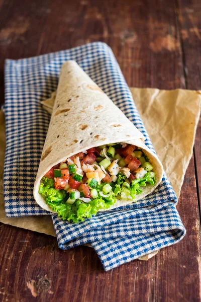 Mexican style tortilla wrap with shrimps, tomatoes, cucumbers, onion on a wooden table for a snack or summer picnic, selective focus