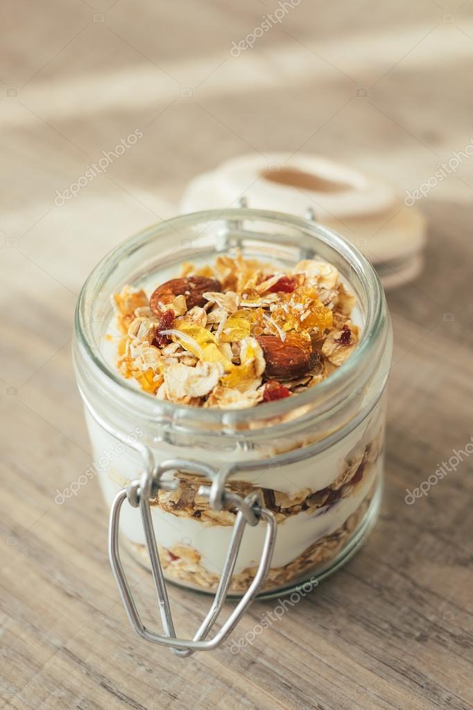 Homemade bircher muesli with toasted rolled oats, dried fruits, nuts, honey and fresh yogurt in