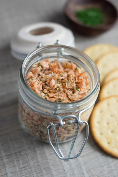 Roasted and smoked salmon and soft cheese spread with dill and butter served with cheese crackers, selective focus