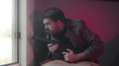 Pencere kenarında silahlı paranoyak bir adam.