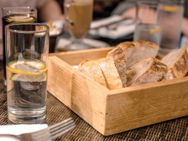 Wooden Box of Fresh Bread and Glasses of Water with Lemon SLices