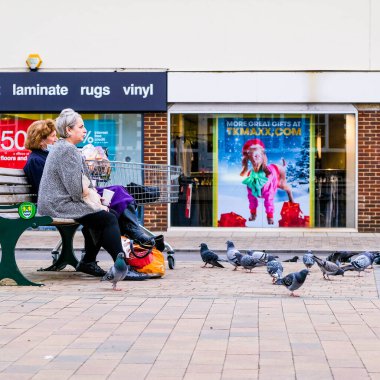 London UK, November 26 2020, Two Women Sitting On A Bench, Outdoors, Feeding Pigeons During UK Winter Lockdown 2020 clipart