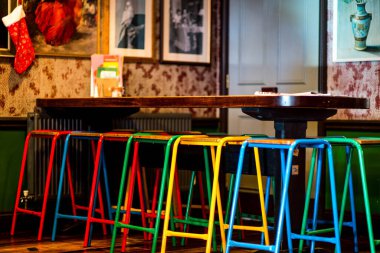 Noel süsleri ve cilalı ahşap döşemeleri olan bir restoranda renkli bar taburesi.