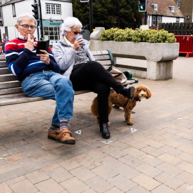 Epsom Surrey London UK, 31 Mart 2021, Açık bir koltukta oturan yaşlı kadın çift ya da kahve ile dinlenen benç