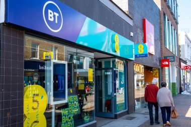 Kingston Upon Thames London UK, 19 Nisan 2021, Anonim bir yaşlı çift yüksek caddedeki bir BT dükkanının önünden geçiyor ya da cep telefonu ya da telefon satıyor.