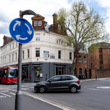 Kingston Thames İngiltere, 07 Mayıs 2021, Bir Araba ve Otobüs mavi trafik işaretli bir kavşağa yaklaşıyor.