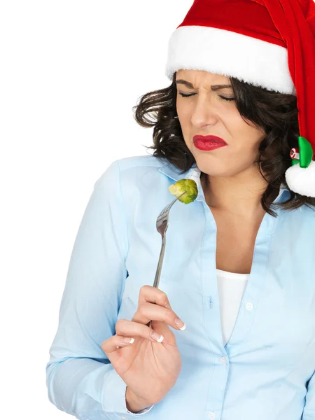 Junge Frau mit Weihnachtsmannhut isst Rosenkohl von einer Gabel — Stockfoto