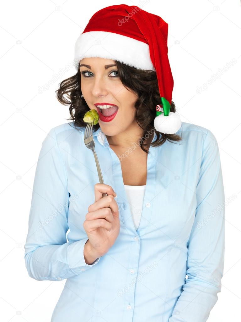 Young Woman in Santa Hat Eating a Brussel Sprout off a Fork