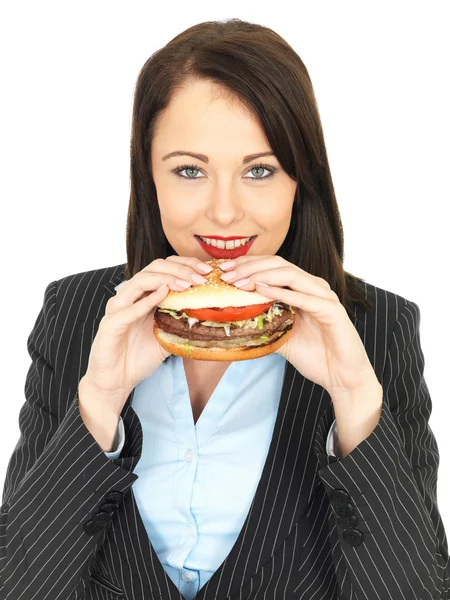 Jonge zakenvrouw eten van een hamburger rundvlees — Stockfoto