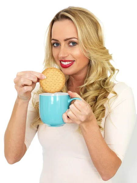 Jonge vrouw Dunking een koekje in een mok thee — Stockfoto