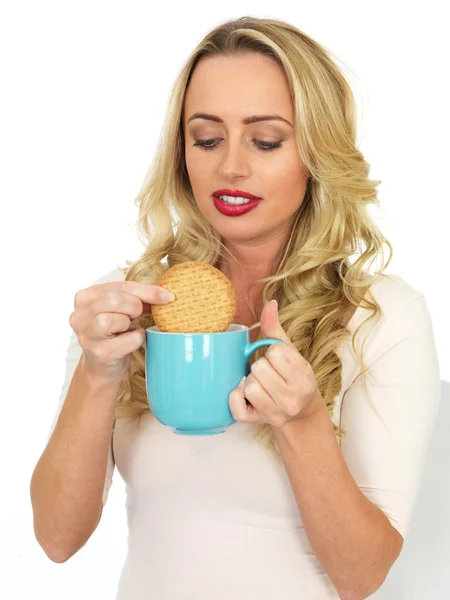 Jonge vrouw Dunking een koekje in een mok thee — Stockfoto