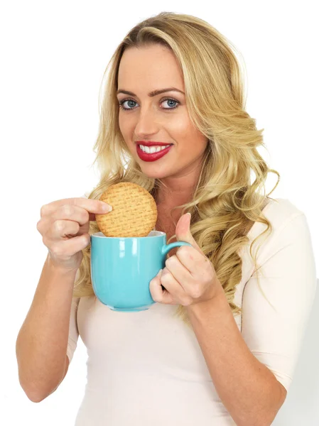Mujer joven Dunking una galleta en una taza de té — Foto de Stock