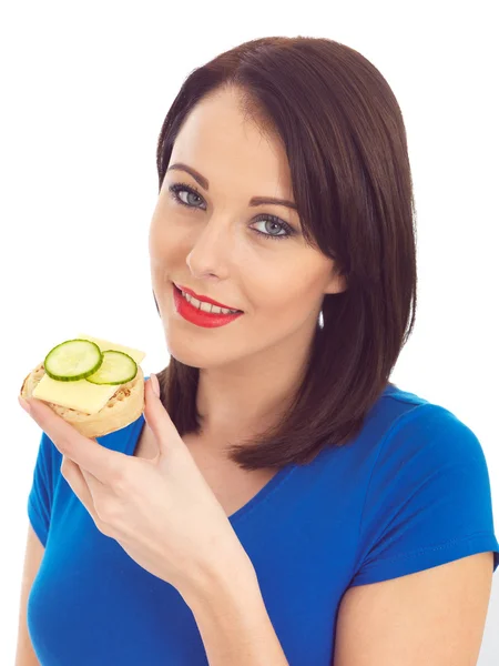 Jovem mulher comendo torrado crrumpet com queijo e pepino — Fotografia de Stock