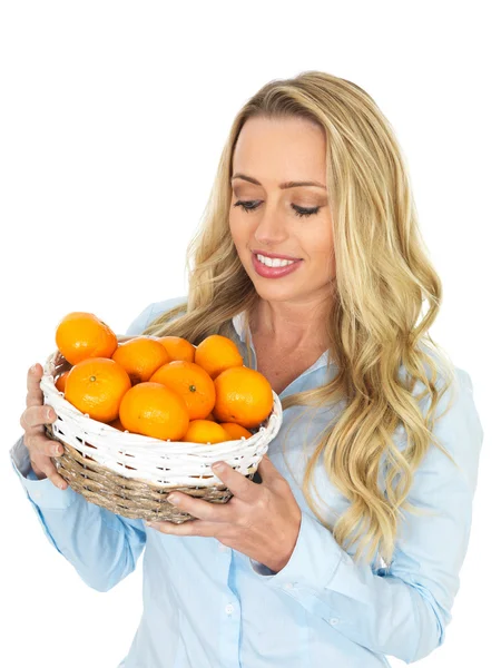 年轻女子捧着一篮橘子 — 图库照片