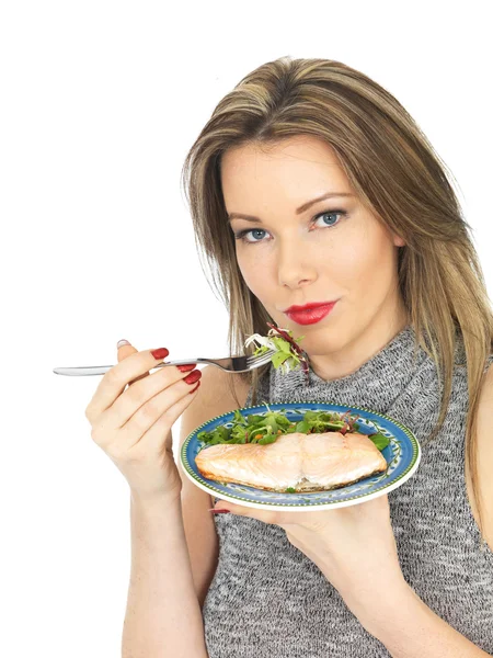 Mujer joven comiendo Slamon escalfado y ensalada —  Fotos de Stock