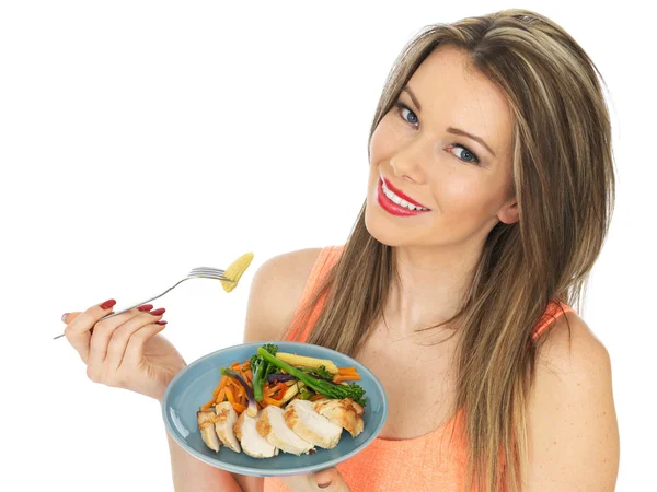 Mladá žena jíst kuře s míchanou zeleninou — Stock fotografie
