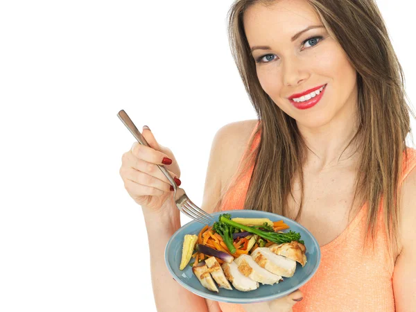 Jeune femme mangeant du poulet aux légumes mélangés — Photo