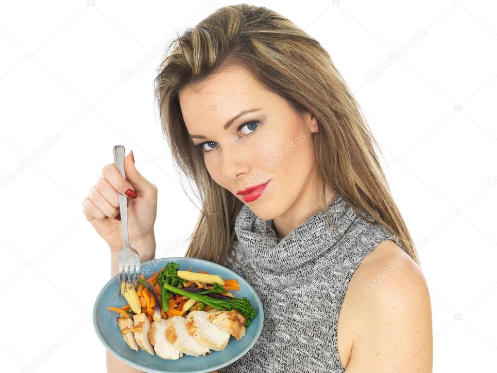Young Woman Eating Chicken Breast with Vegetables